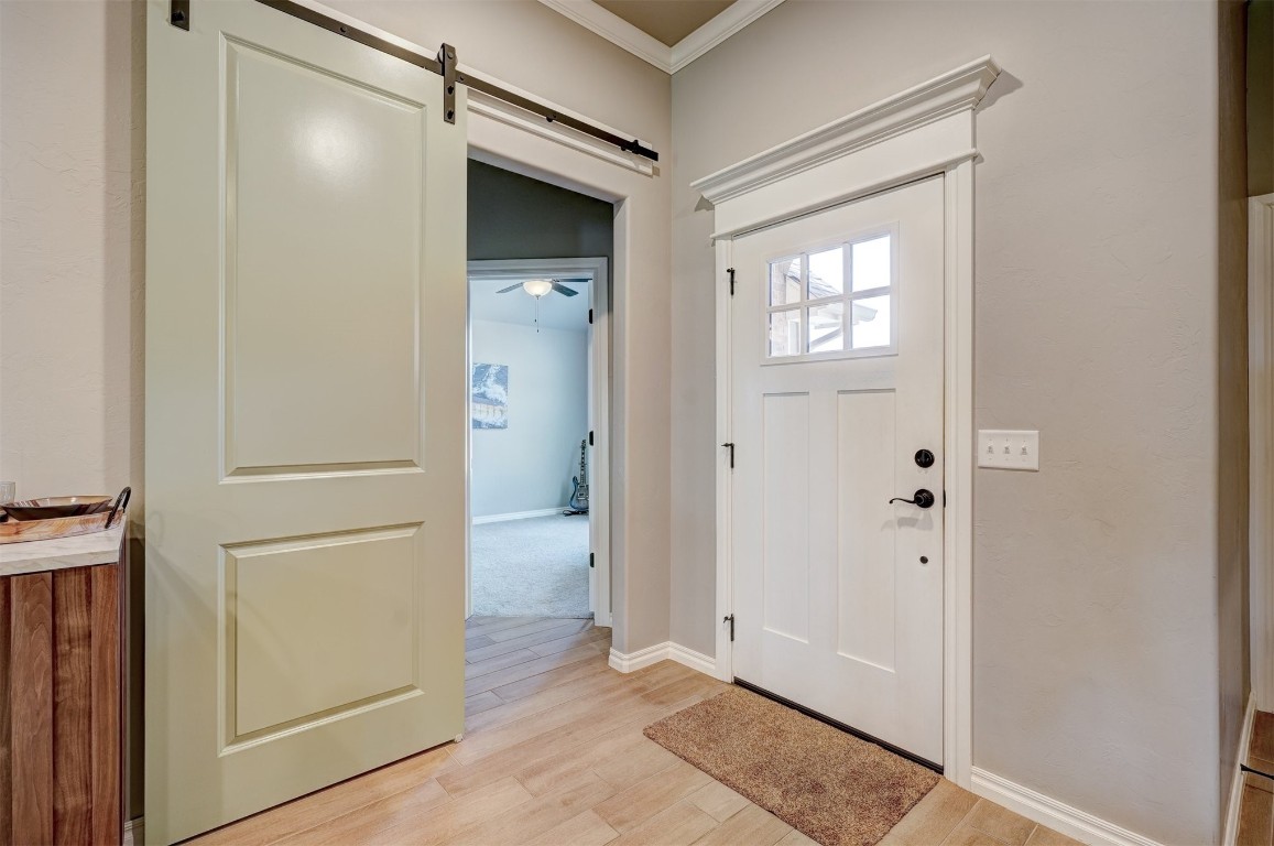 18700 Lazy Grove Drive, Edmond, OK 73012 foyer featuring crown molding, light wood-type flooring, and a barn door