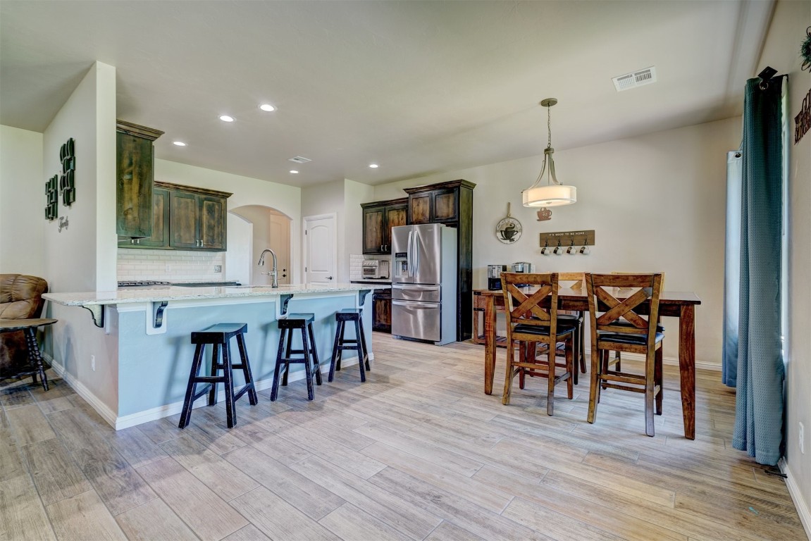 551 Canyon Creek Lane, Guthrie, OK 73044 kitchen with backsplash, light hardwood / wood-style flooring, dark brown cabinets, and stainless steel fridge