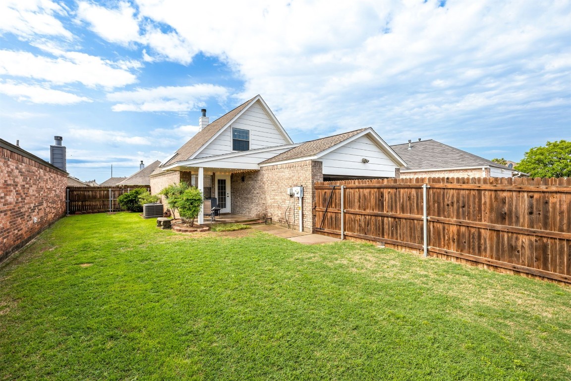 1007 SW 23rd Street, Moore, OK 73170 back of property with central AC unit and a lawn