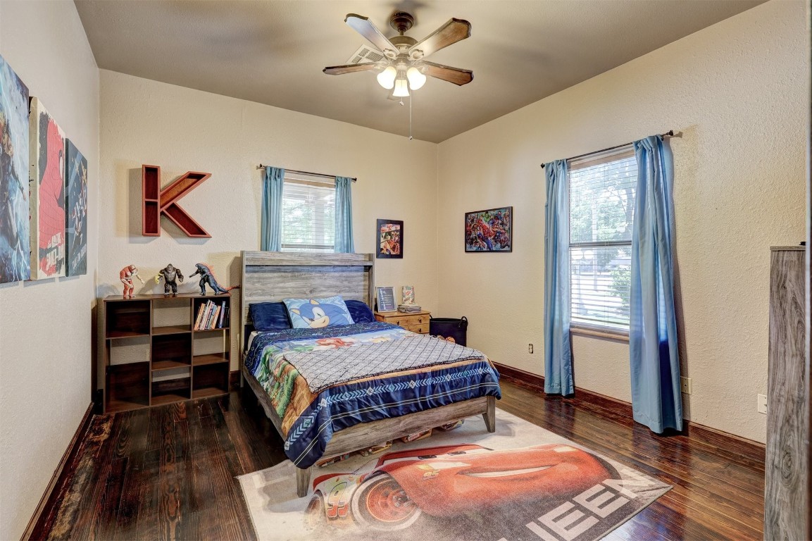1008 Sunset Drive, El Reno, OK 73036 bedroom with dark hardwood / wood-style flooring, multiple windows, and ceiling fan