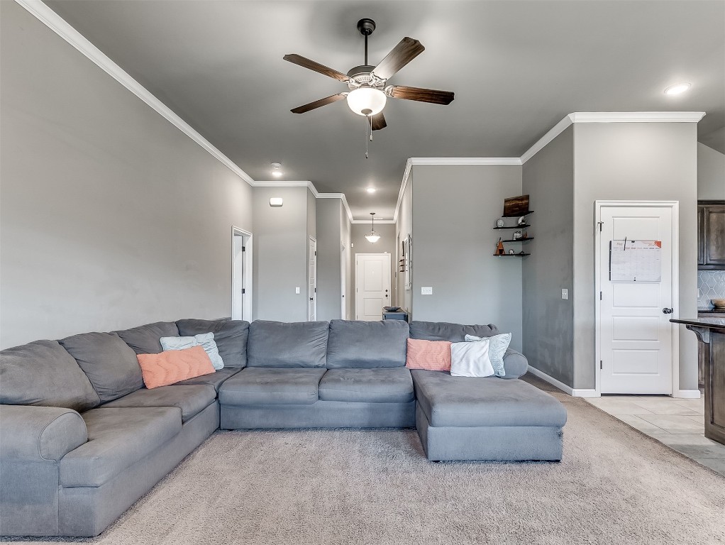 6716 NW 158th Street, Edmond, OK 73013 living room featuring light carpet, ceiling fan, and ornamental molding