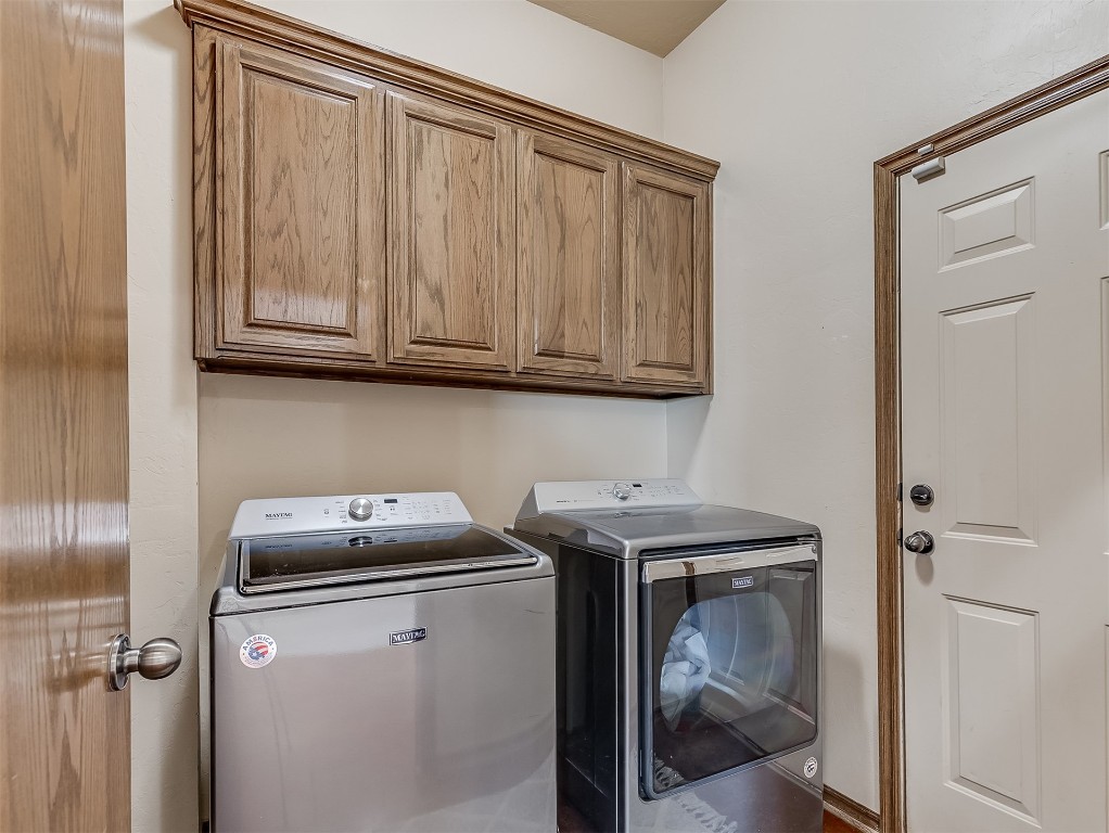 3952 NE Arrowhead Road, Piedmont, OK 73078 laundry room with cabinets and washing machine and clothes dryer