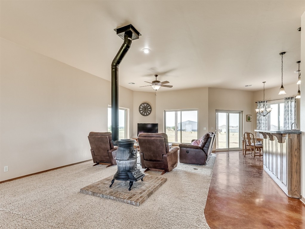 3952 NE Arrowhead Road, Piedmont, OK 73078 living room featuring ceiling fan with notable chandelier, a wood stove, and concrete floors