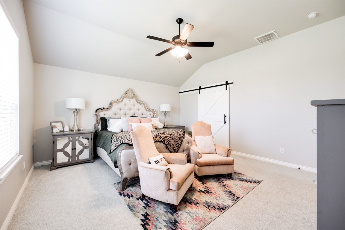 2321 NW 187th Terrace, Edmond, OK 73012 bedroom featuring vaulted ceiling, ceiling fan, a barn door, and carpet floors