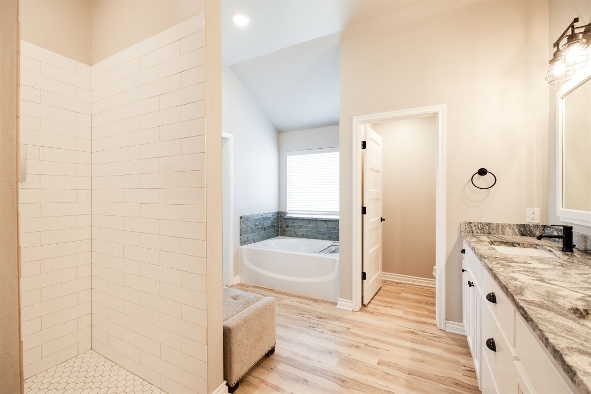 2321 NW 187th Terrace, Edmond, OK 73012 bathroom with lofted ceiling, vanity, hardwood / wood-style flooring, and a bath