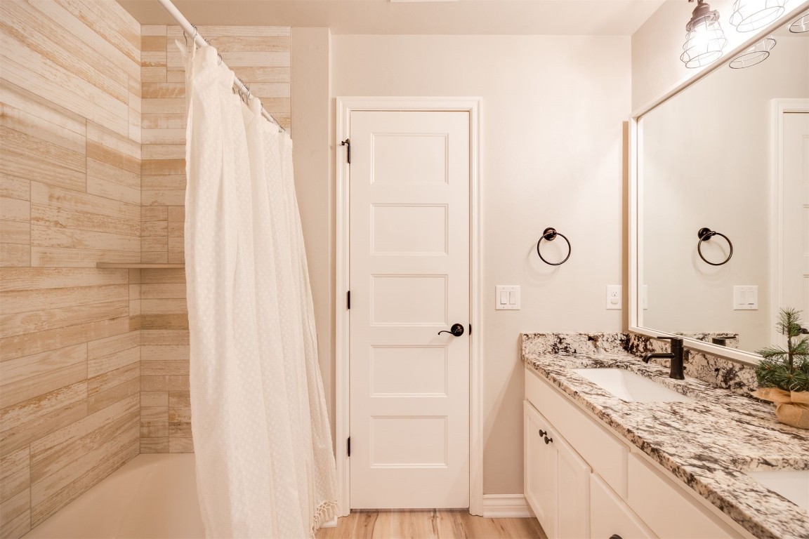 2321 NW 187th Terrace, Edmond, OK 73012 bathroom featuring vanity, hardwood / wood-style flooring, and shower / bathtub combination with curtain