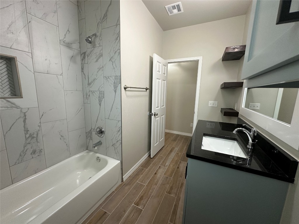 3209 N Pioneer Street, Oklahoma City, OK 73107 bathroom featuring tiled shower / bath, vanity, and hardwood / wood-style floors