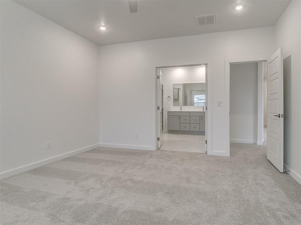 8004 NW 152nd Street, Edmond, OK 73013 unfurnished bedroom featuring ensuite bath, ceiling fan, and light carpet