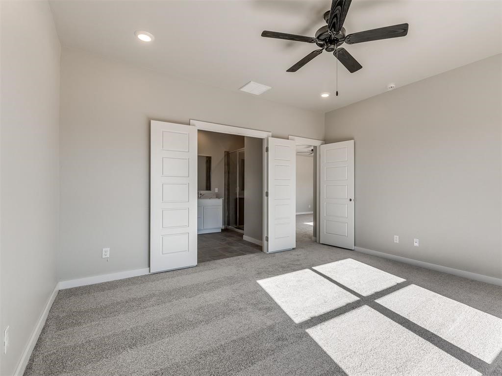8112 NW 153rd Street, Edmond, OK 73013 unfurnished bedroom with ceiling fan, carpet, and connected bathroom