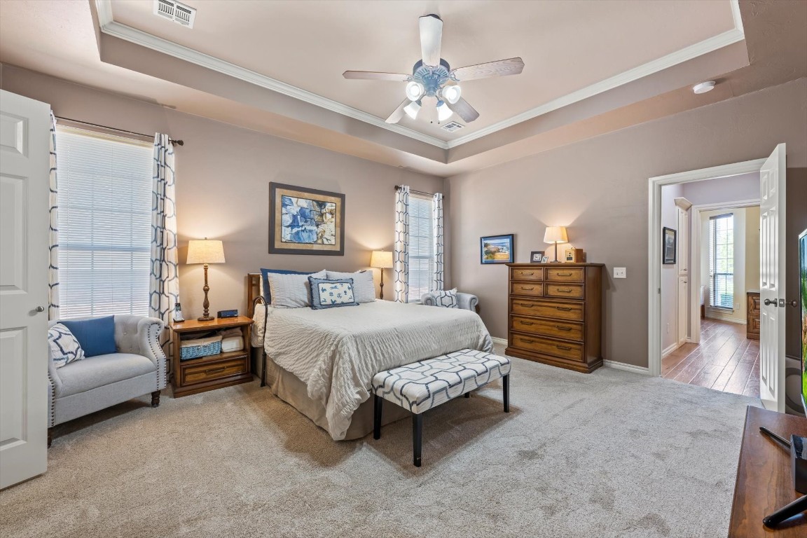 1816 Redland Drive, Edmond, OK 73003 bedroom featuring ornamental molding, ceiling fan, a raised ceiling, and carpet floors