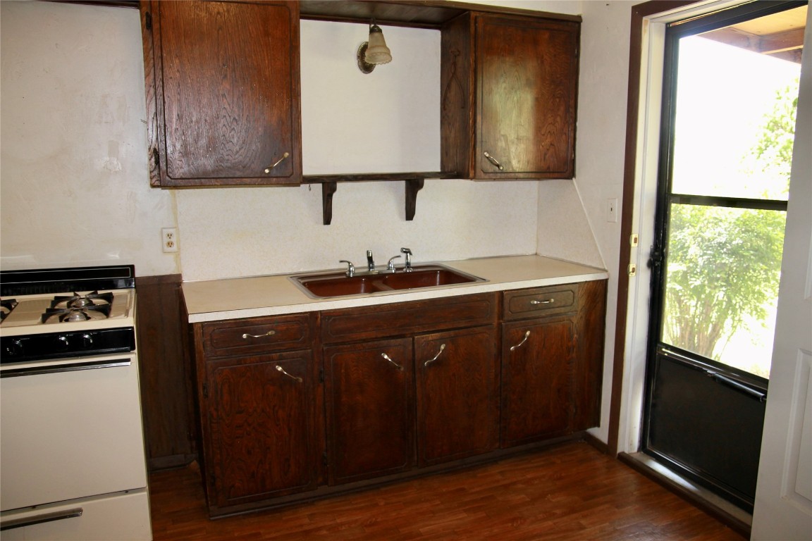 1307 N Broad Street, Guthrie, OK 73044 kitchen with white range, dark hardwood / wood-style flooring, dark brown cabinets, and sink