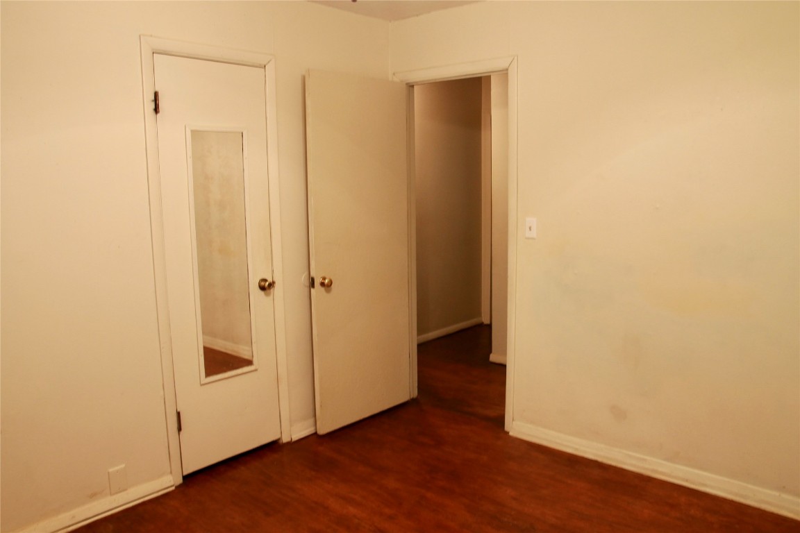 1307 N Broad Street, Guthrie, OK 73044 unfurnished bedroom featuring dark wood-type flooring