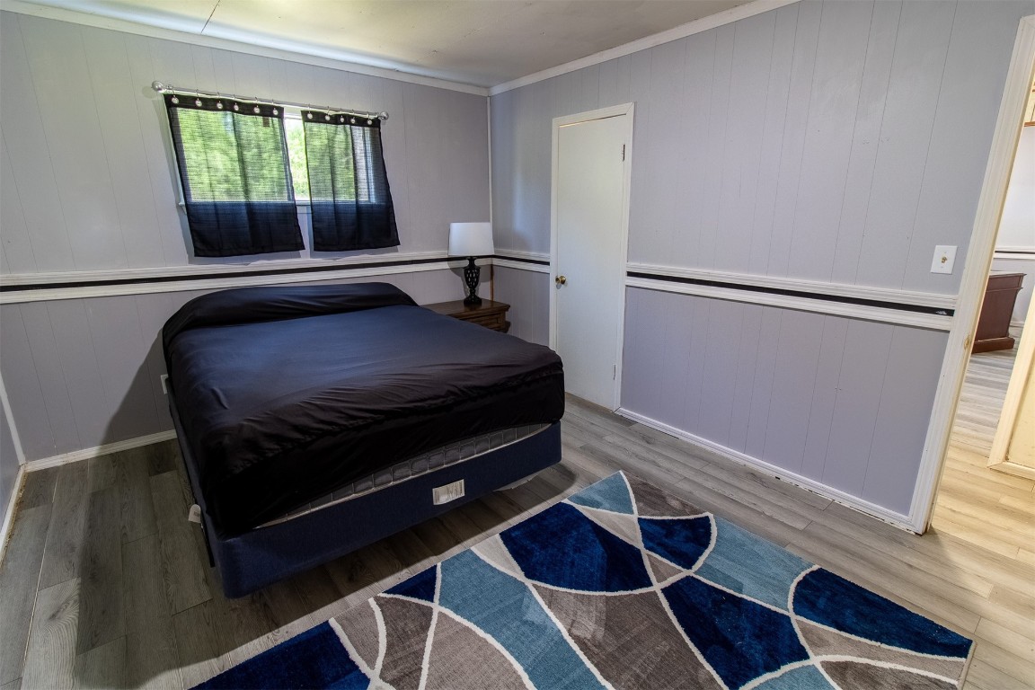 119 W Tennyson Avenue, Tecumseh, OK 74873 bedroom with hardwood / wood-style flooring and crown molding