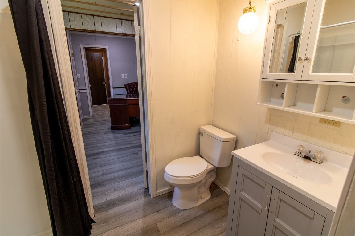 119 W Tennyson Avenue, Tecumseh, OK 74873 bathroom with wood-type flooring, vanity with extensive cabinet space, tasteful backsplash, and toilet
