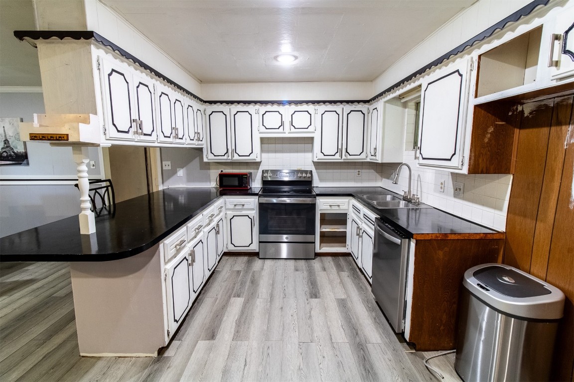 119 W Tennyson Avenue, Tecumseh, OK 74873 kitchen with light hardwood / wood-style flooring, backsplash, kitchen peninsula, stainless steel appliances, and sink
