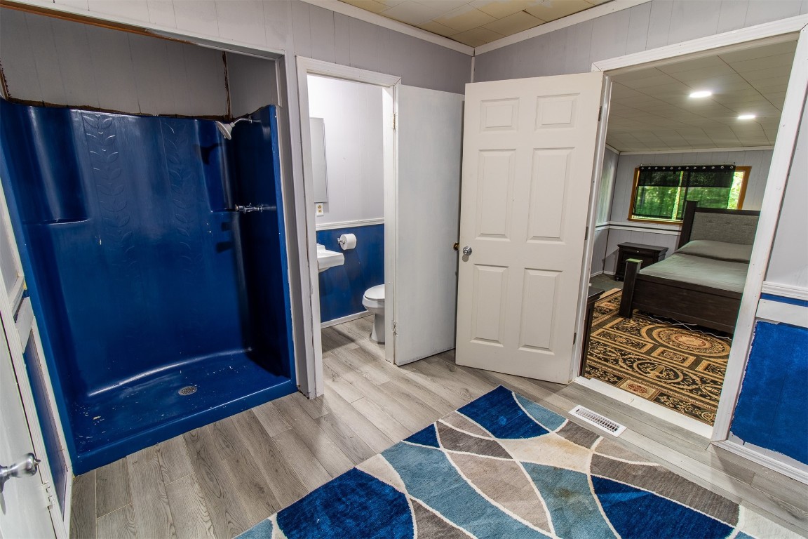 119 W Tennyson Avenue, Tecumseh, OK 74873 bathroom featuring wood-type flooring, crown molding, and toilet