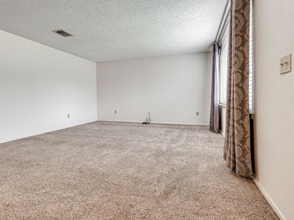 7613 NW 113th Place, Oklahoma City, OK 73162 empty room with carpet flooring and a textured ceiling