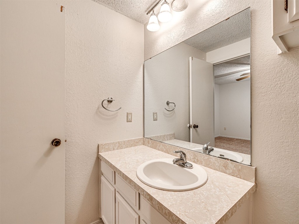 7613 NW 113th Place, Oklahoma City, OK 73162 bathroom featuring a textured ceiling and large vanity