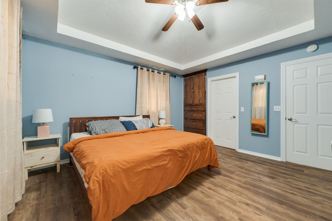 2825 NW 11th Street, Oklahoma City, OK 73107 bedroom featuring a raised ceiling, light hardwood / wood-style floors, ceiling fan, and ensuite bath