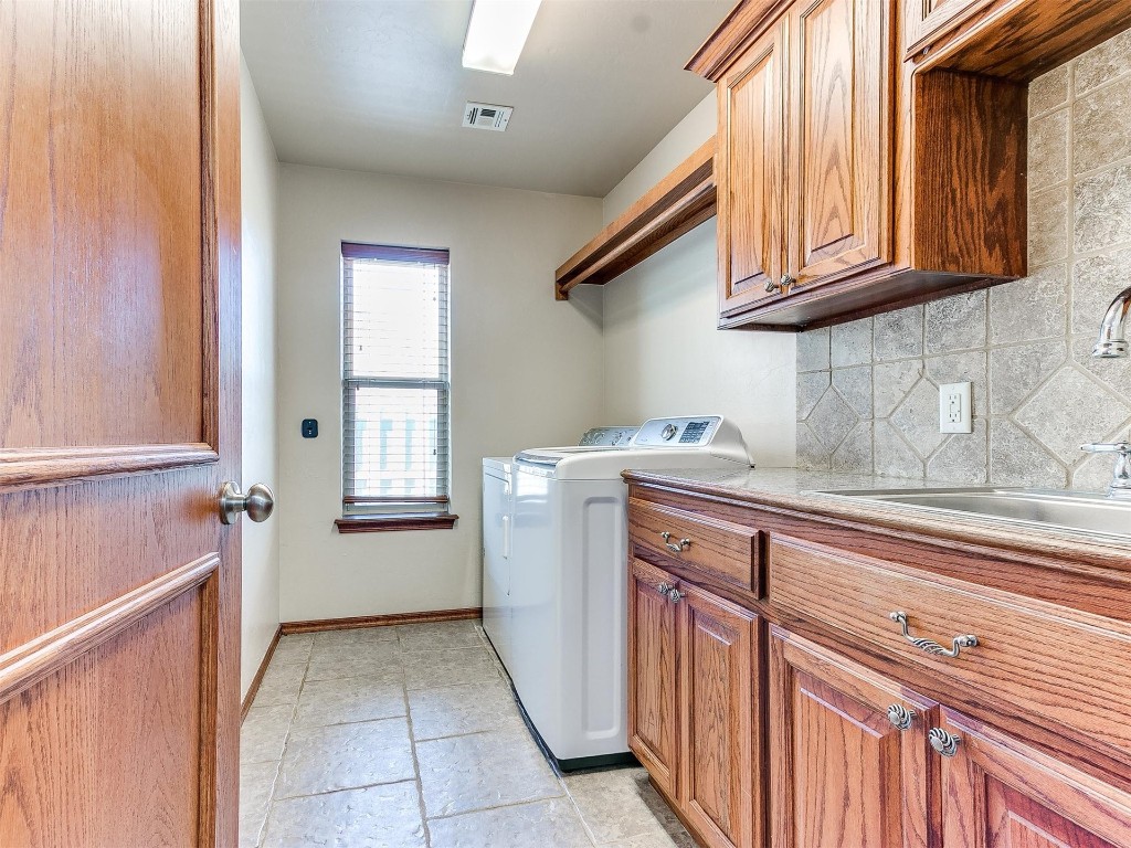 749 Gallant Fox Court, Edmond, OK 73025 washroom featuring independent washer and dryer, cabinets, sink, and light tile flooring