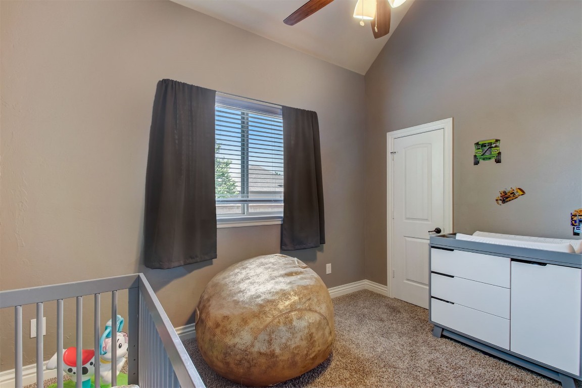 2816 Indian Grass Court, Edmond, OK 73013 carpeted bedroom featuring vaulted ceiling, ceiling fan, and a nursery area