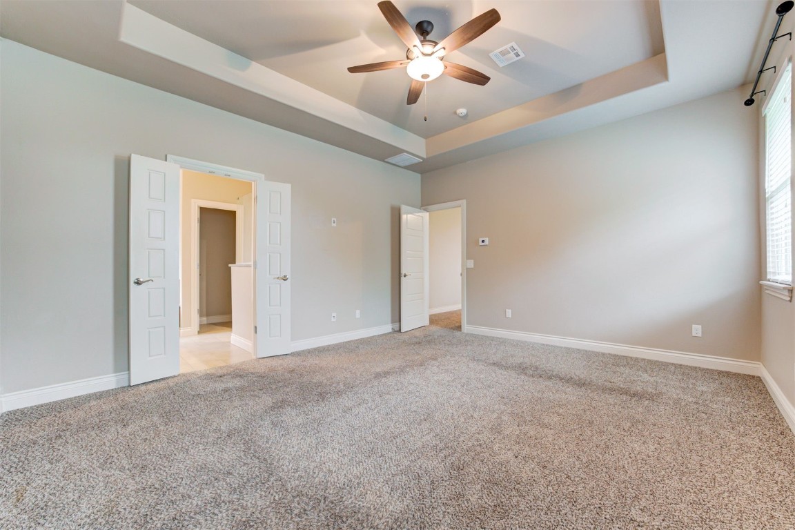 10508 Glover River Drive, Yukon, OK 73099 spare room featuring a wealth of natural light, ceiling fan, carpet floors, and a tray ceiling