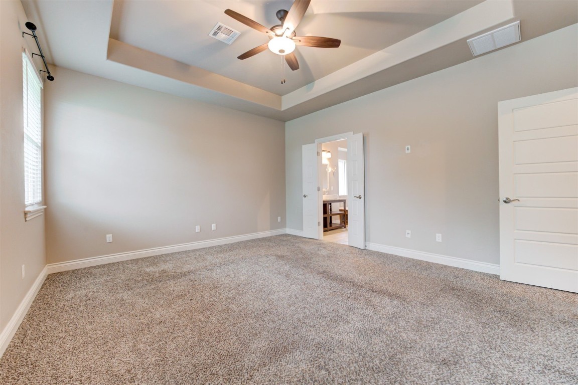 10508 Glover River Drive, Yukon, OK 73099 empty room with ceiling fan, carpet floors, and a tray ceiling