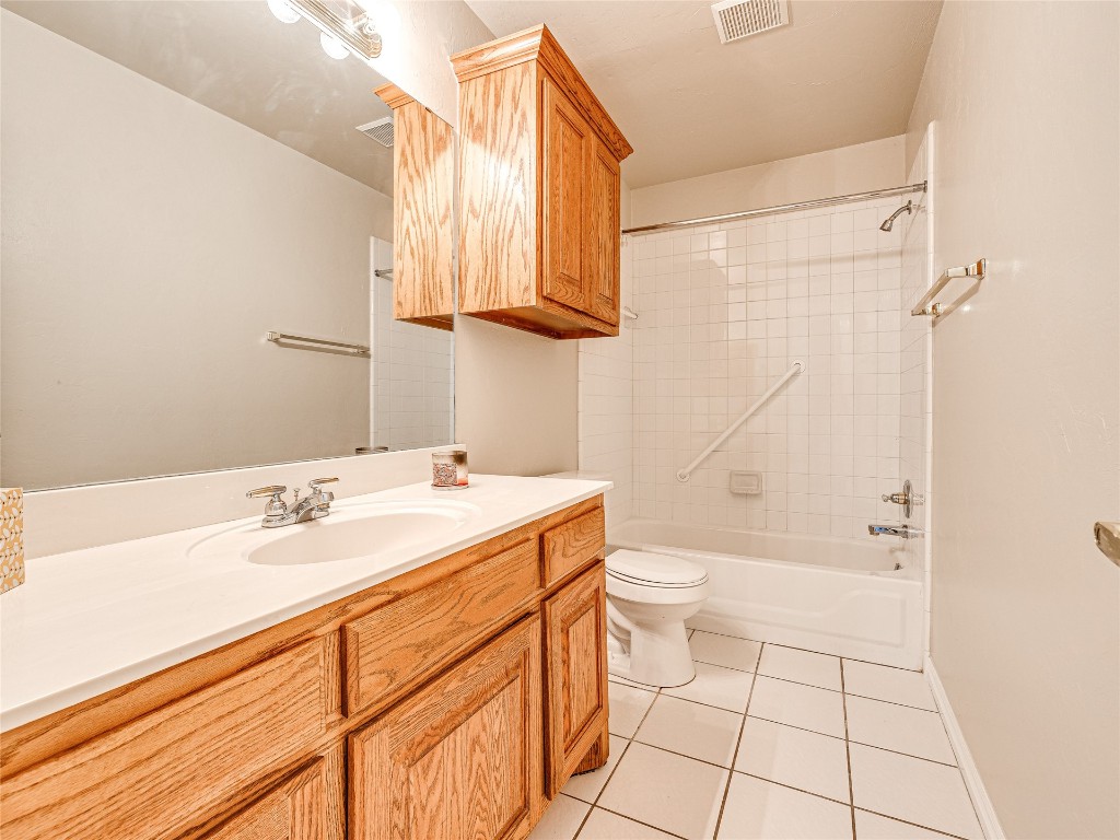 6913 NW 133rd Terrace, Oklahoma City, OK 73142 full bathroom with tiled shower / bath combo, vanity, toilet, and tile flooring