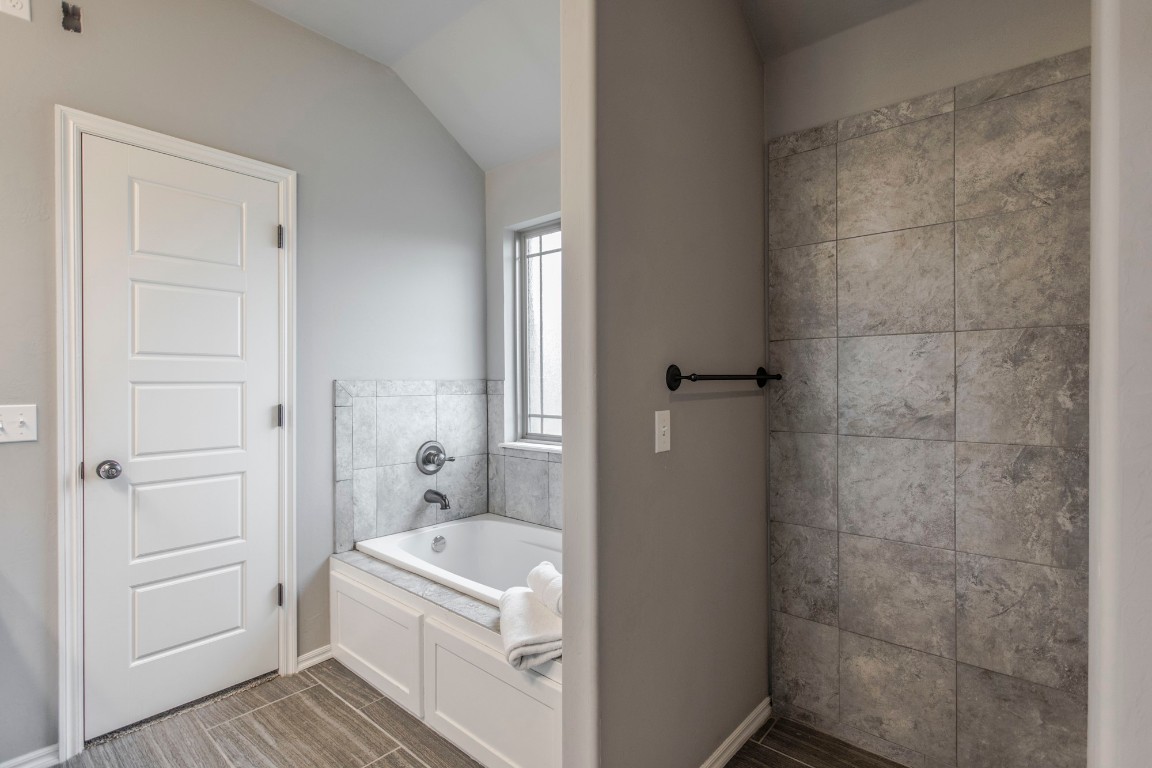 4604 Oasis Lane, Yukon, OK 73099 bathroom with vaulted ceiling, tile floors, and tiled bath
