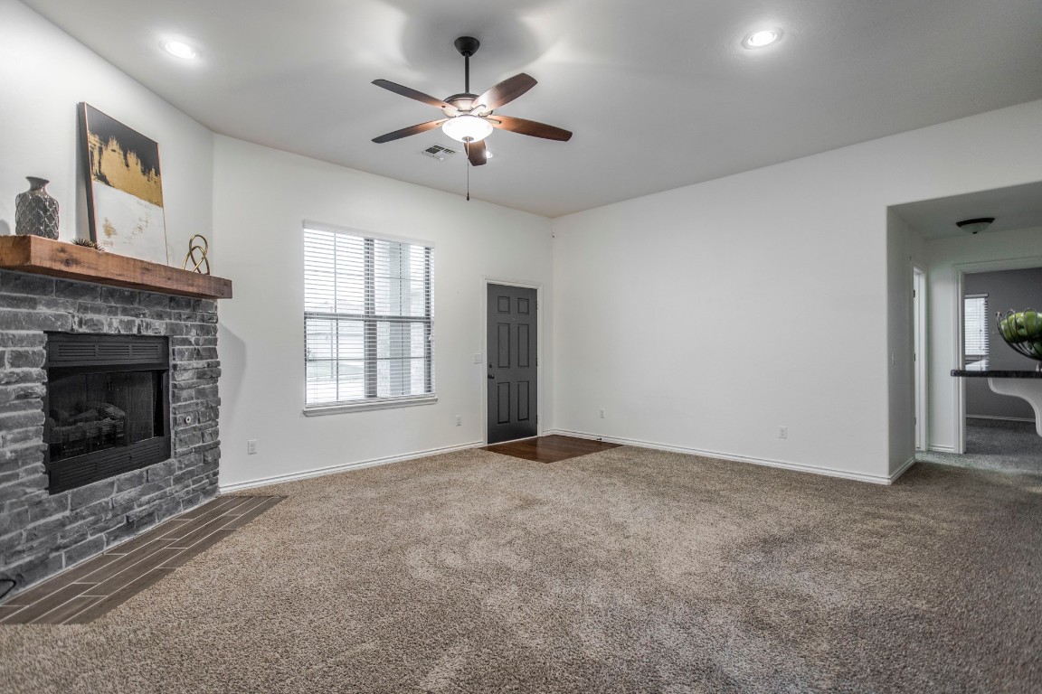 4604 Oasis Lane, Yukon, OK 73099 unfurnished living room with ceiling fan, carpet flooring, and a brick fireplace