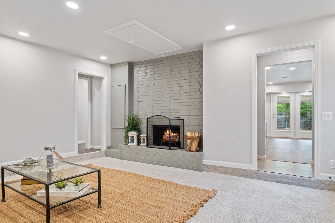717 Howard Court, Edmond, OK 73003 living room featuring a brick fireplace and carpet flooring