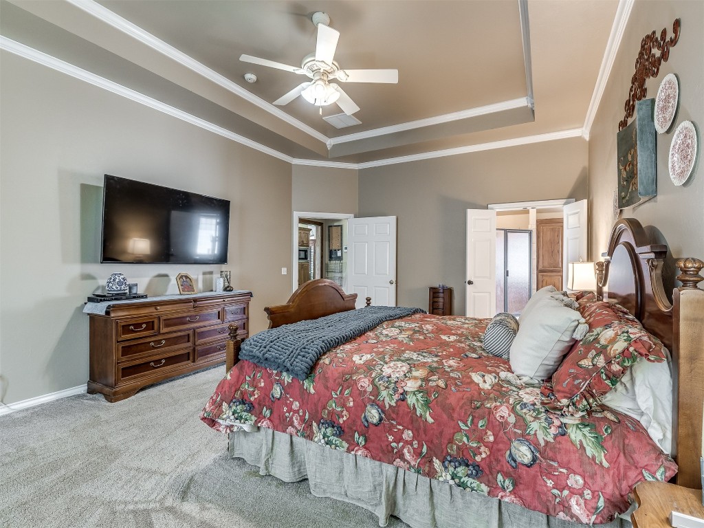 10621 Sundance Avenue, Yukon, OK 73099 bedroom featuring ornamental molding, carpet, ceiling fan, and a tray ceiling