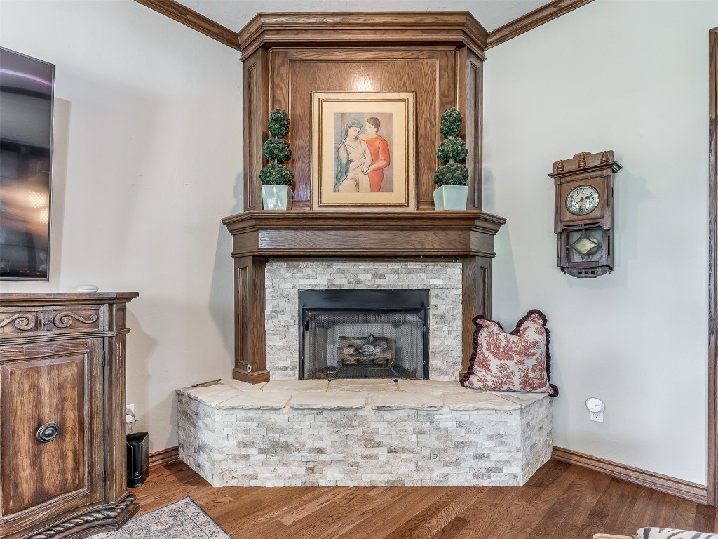 10621 Sundance Avenue, Yukon, OK 73099 living room featuring ornamental molding, a stone fireplace, and wood-type flooring