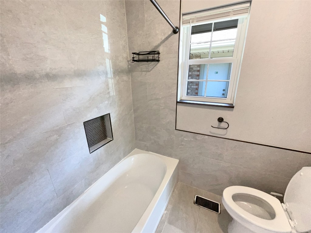 6645 Whitehall Drive, Oklahoma City, OK 73132 bathroom featuring tile flooring, tile walls, tiled shower / bath combo, and toilet