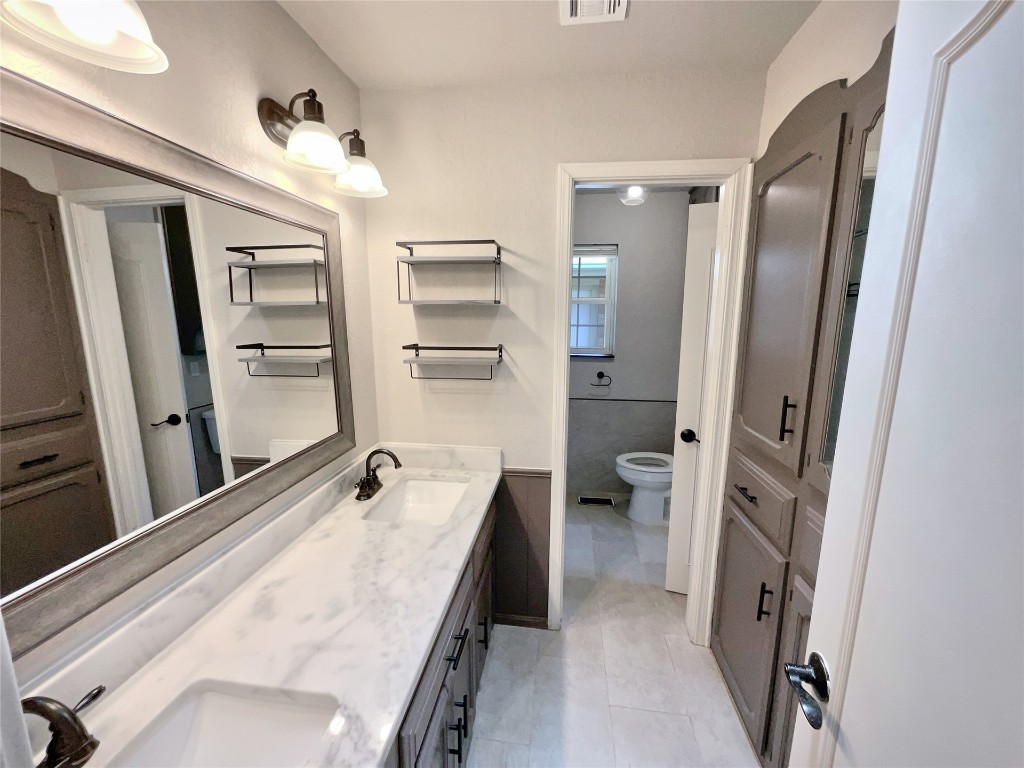 6645 Whitehall Drive, Oklahoma City, OK 73132 bathroom with double vanity, toilet, and tile flooring