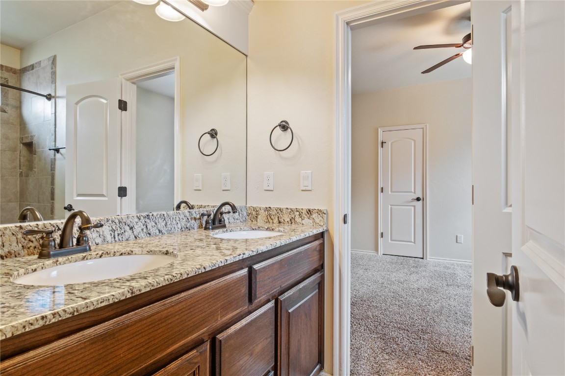 16209 Scissortail Drive, Edmond, OK 73013 bathroom with double sink, tiled shower, ceiling fan, and large vanity