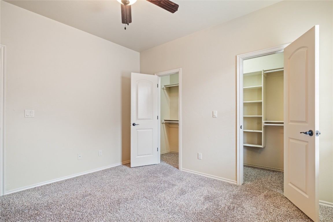 16209 Scissortail Drive, Edmond, OK 73013 unfurnished bedroom featuring a walk in closet, ceiling fan, and carpet floors