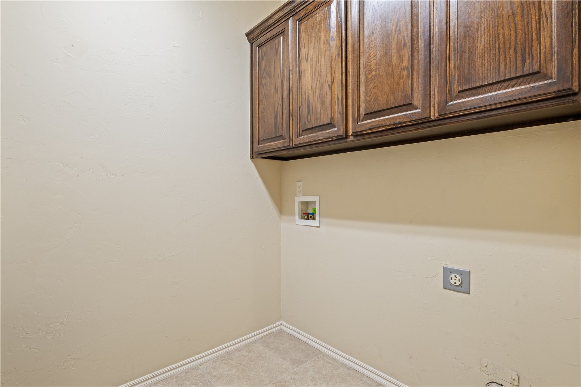 16209 Scissortail Drive, Edmond, OK 73013 laundry room with washer hookup, hookup for an electric dryer, cabinets, and light tile floors