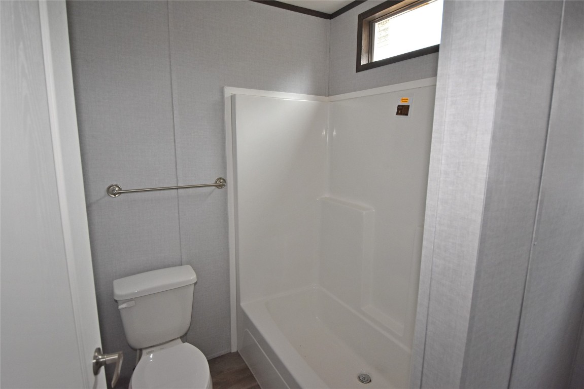 5551 S Douglas Boulevard, Guthrie, OK 73044 bathroom featuring wood-type flooring, bathing tub / shower combination, and toilet