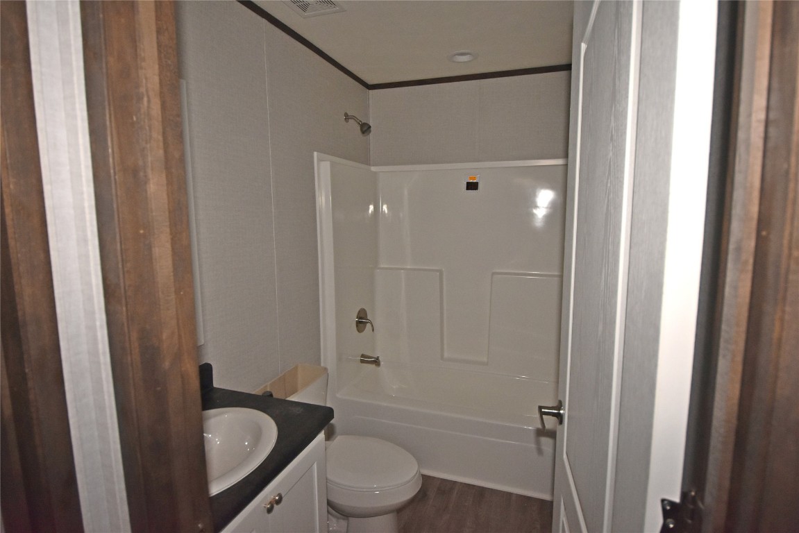 5551 S Douglas Boulevard, Guthrie, OK 73044 full bathroom featuring hardwood / wood-style floors, vanity, tub / shower combination, and toilet