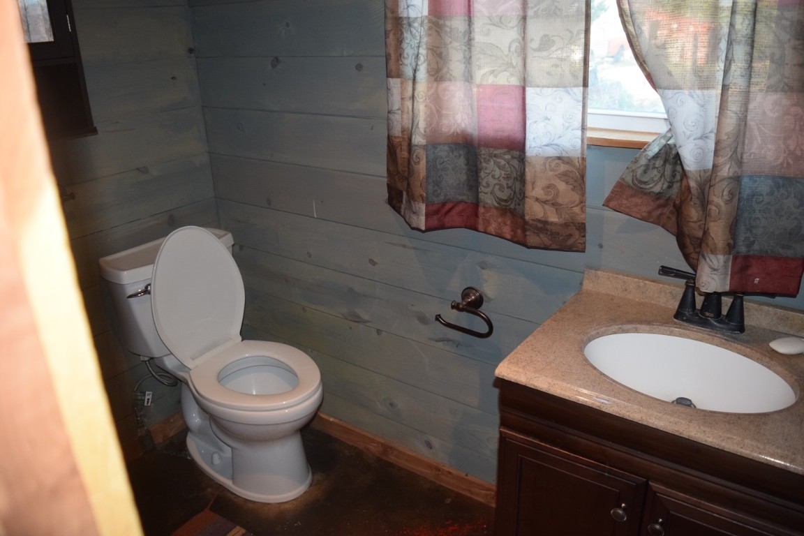 18633 N Santa Fe Avenue, Mulhall, OK 73063 bathroom featuring wooden walls, toilet, and vanity