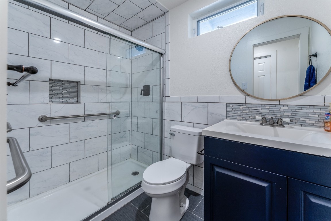 620 Nebraska Street, Norman, OK 73069 bathroom featuring tile walls, walk in shower, vanity with extensive cabinet space, toilet, and tasteful backsplash