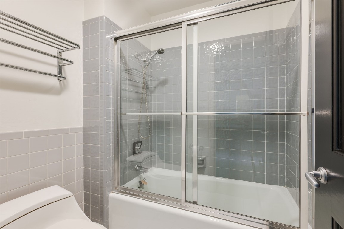 3109 NW 63rd Street, #39, Oklahoma City, OK 73116 bathroom with tile walls, toilet, and enclosed tub / shower combo