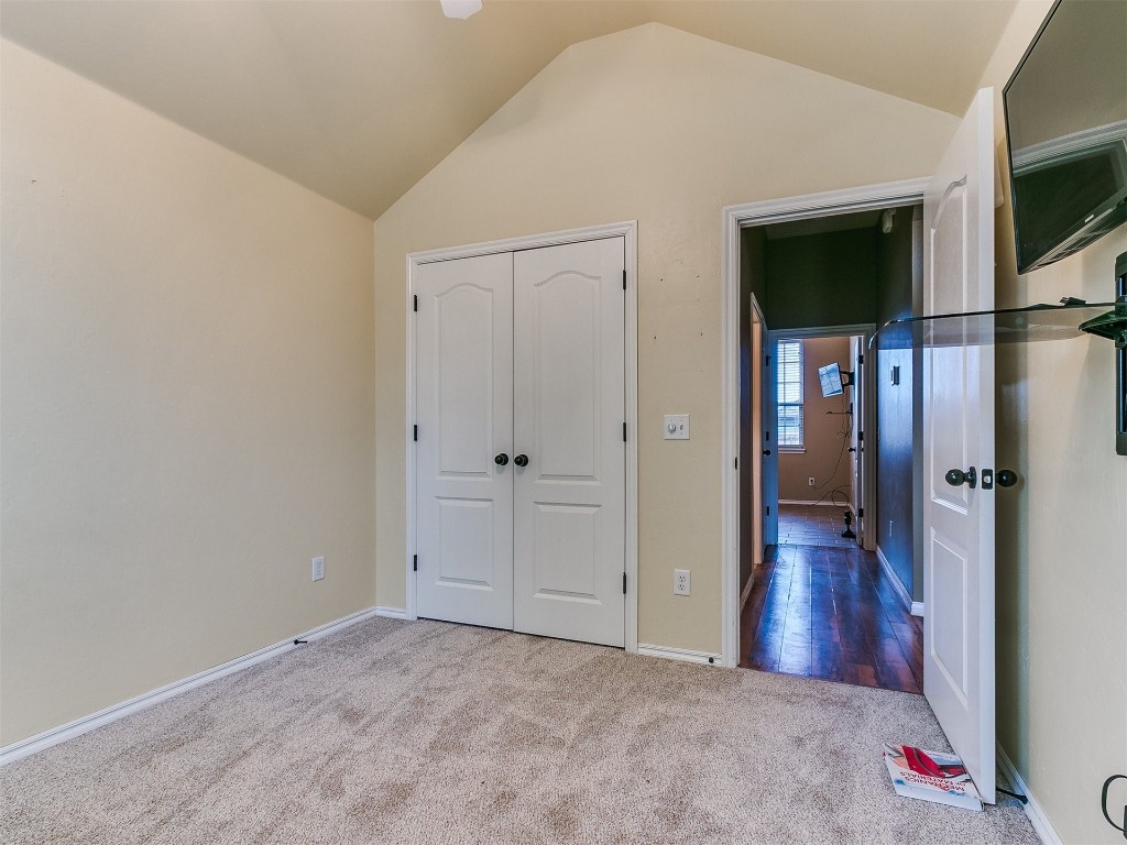 9101 Crooked Creek Lane, Moore, OK 73160 unfurnished bedroom with light colored carpet, vaulted ceiling, and a closet