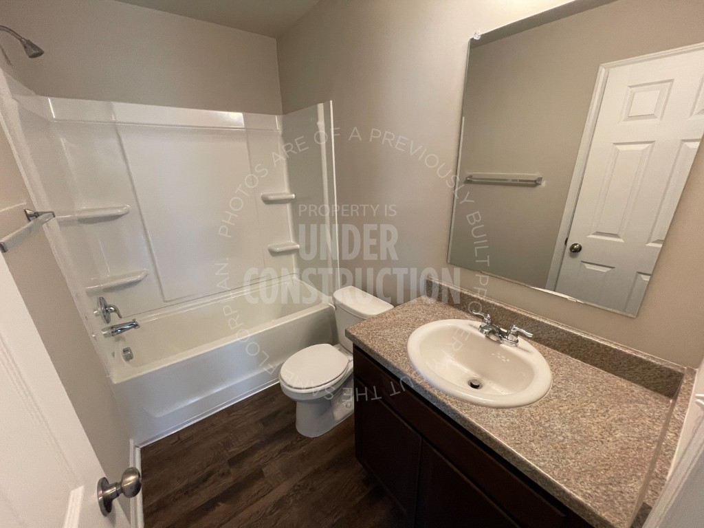 1202 Foal Drive, Guthrie, OK 73044 full bathroom featuring hardwood / wood-style floors, oversized vanity, toilet, and bathing tub / shower combination