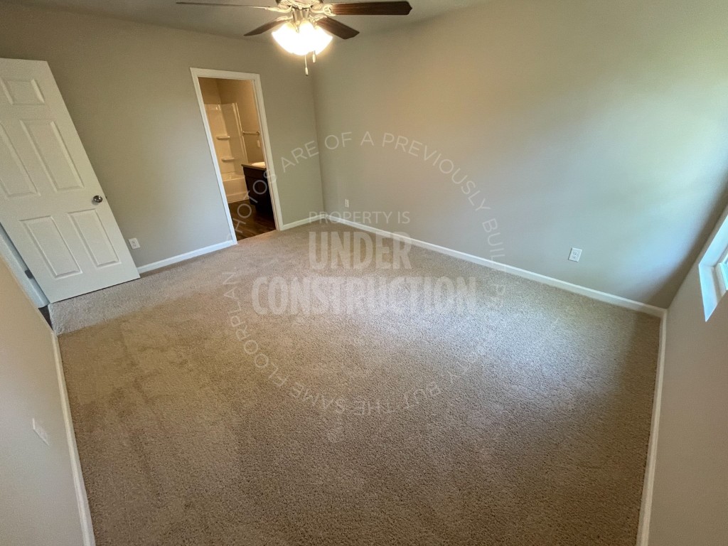 1202 Foal Drive, Guthrie, OK 73044 unfurnished bedroom featuring connected bathroom, ceiling fan, and carpet