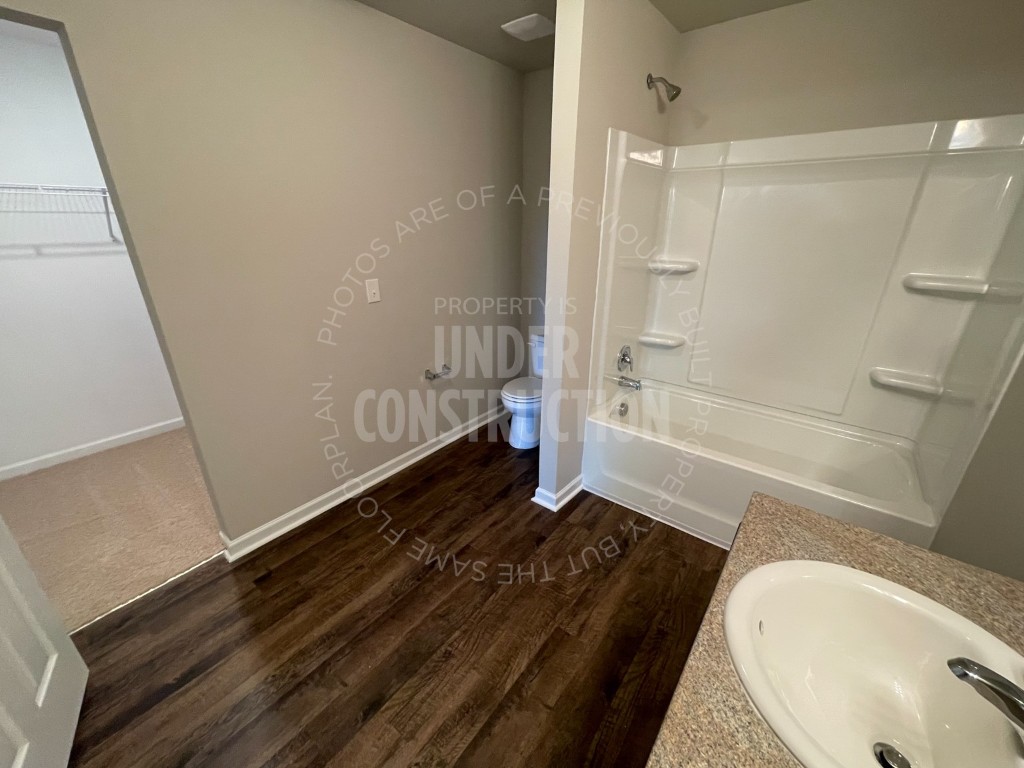 1202 Foal Drive, Guthrie, OK 73044 full bathroom with sink, washtub / shower combination, toilet, and hardwood / wood-style floors