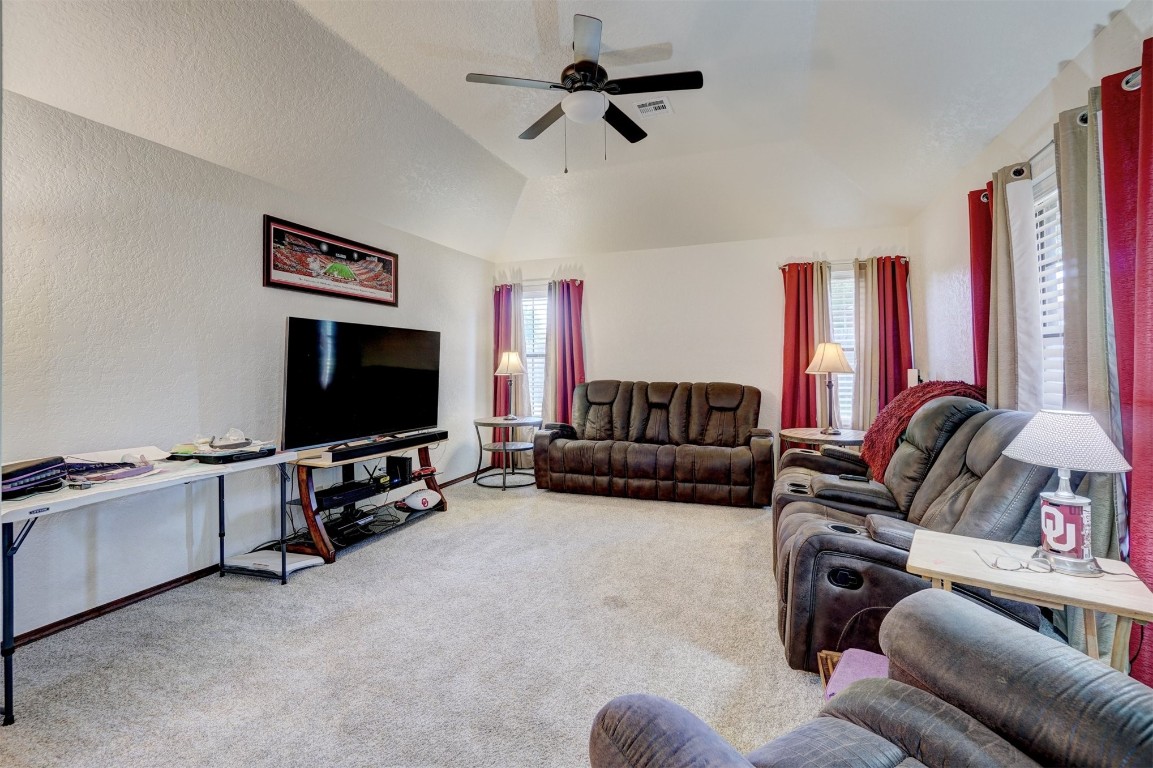1816 NW 176th Street, Edmond, OK 73012 carpeted living room featuring ceiling fan and lofted ceiling