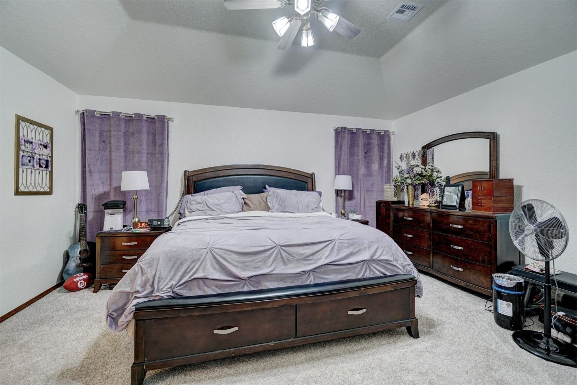 1816 NW 176th Street, Edmond, OK 73012 bedroom with light colored carpet, vaulted ceiling, and ceiling fan
