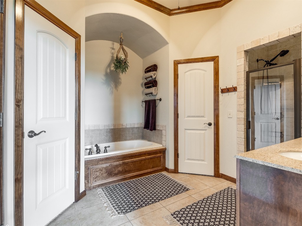 10521 NW 49th Street, Yukon, OK 73099 bathroom featuring vanity, tile floors, crown molding, and plus walk in shower